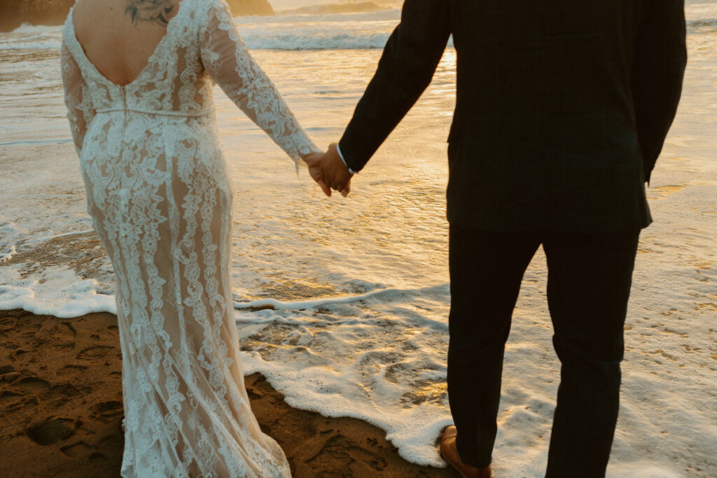 couple holding hands over ocean elopement